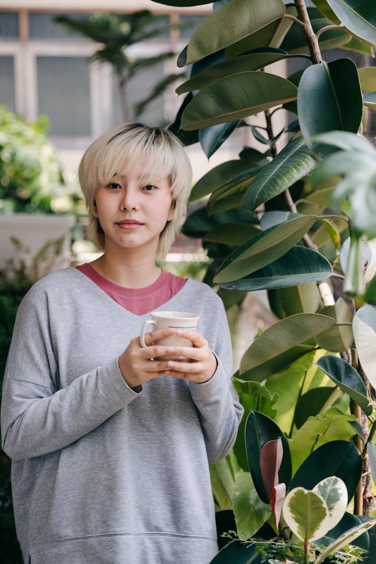 Calm Woman With Cup Of Drink In Garden