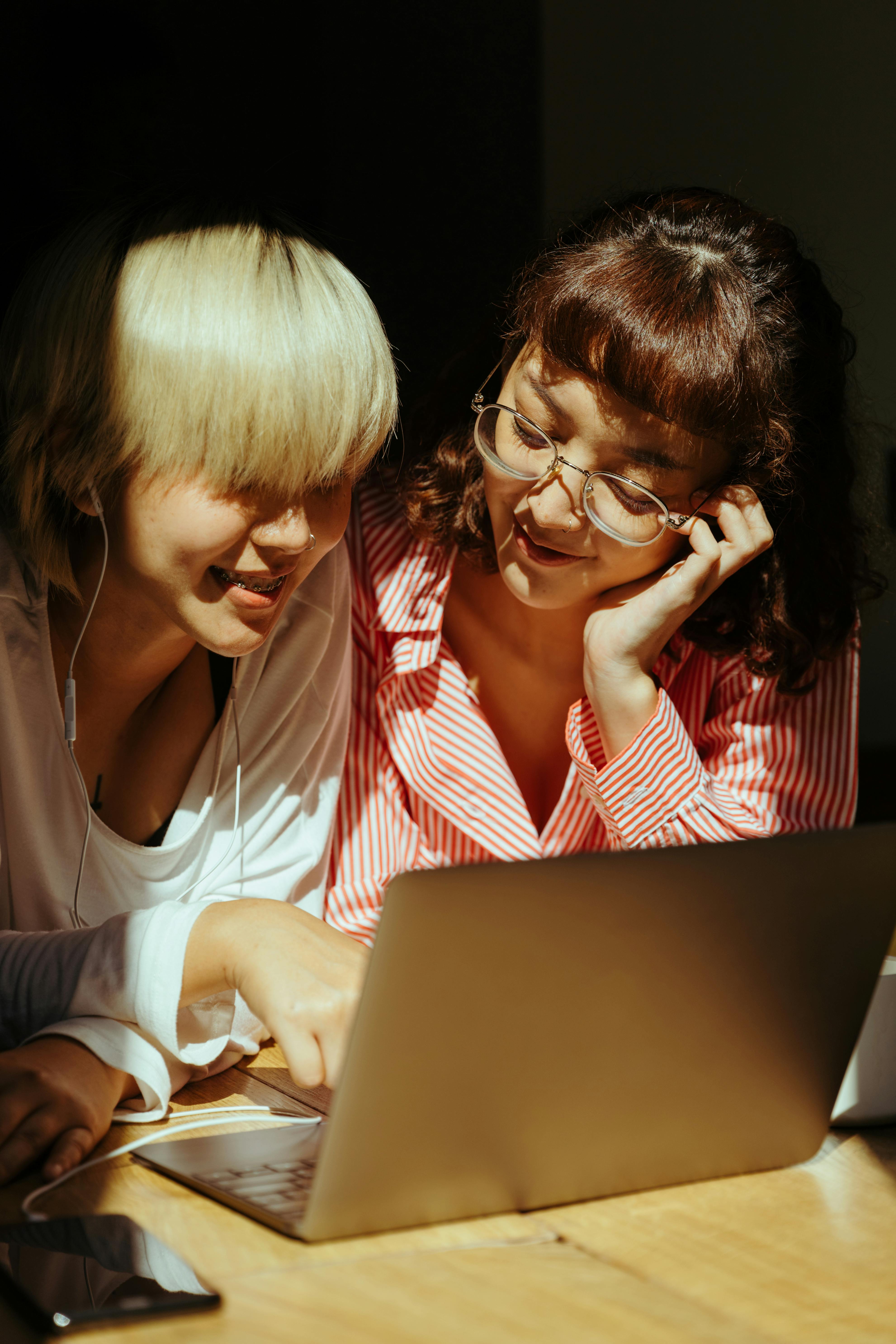 cheerful sisters using laptop together