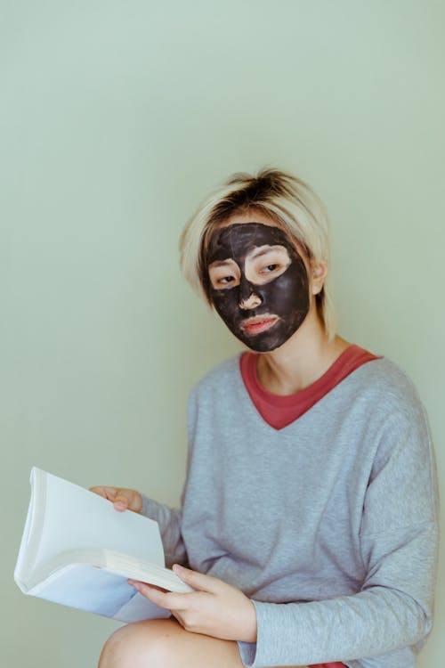 Woman with facial mask reading book