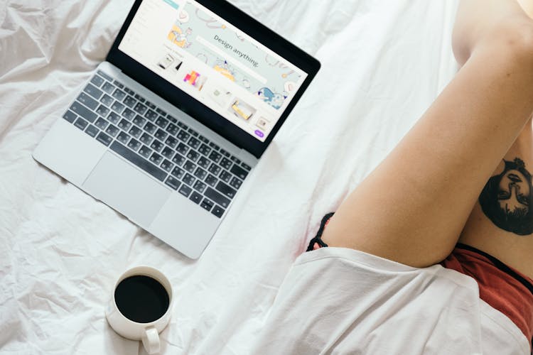 Crop Woman Using Laptop In Bed At Home