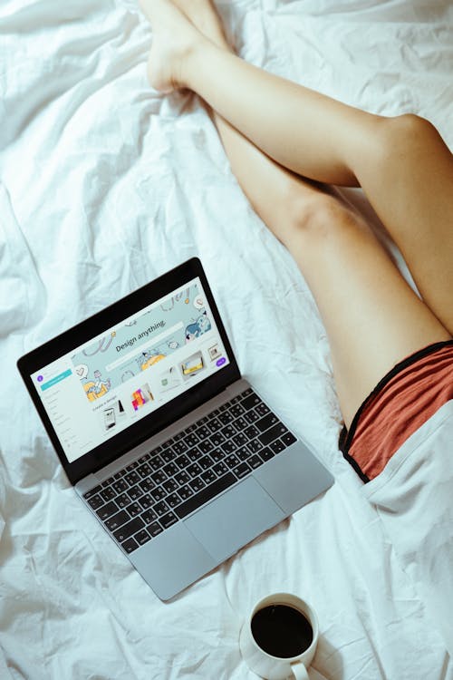 Free Crop woman with laptop and coffee in bed at home Stock Photo