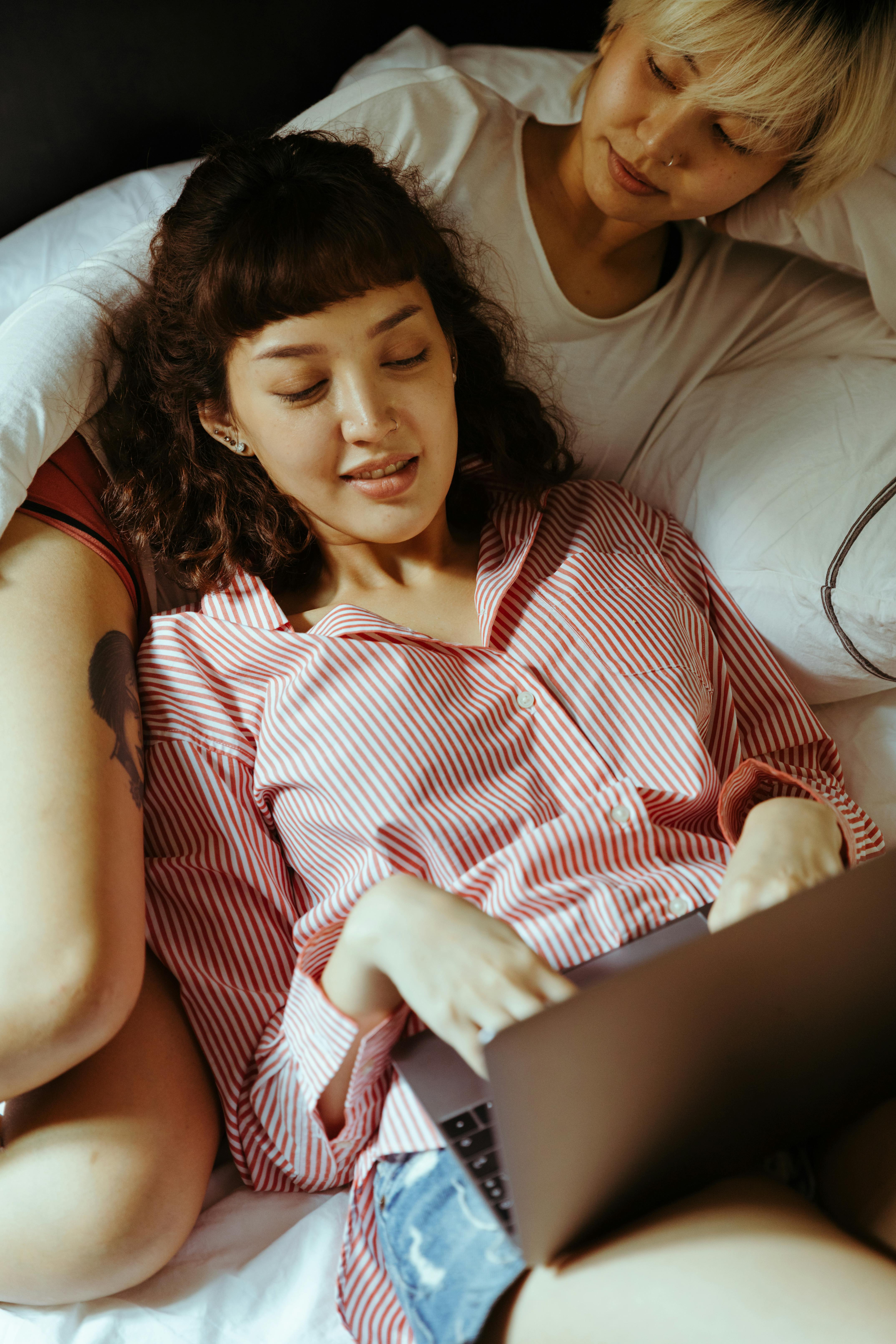 woman using a laptop and reclining on her girlfriend