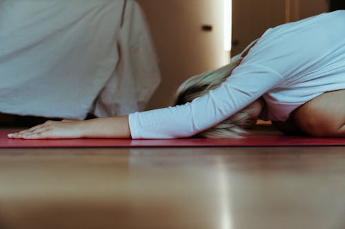 Young female practicing yoga at home wearing casual clothes and stretching body while doing extended child asana during weekend at morning time