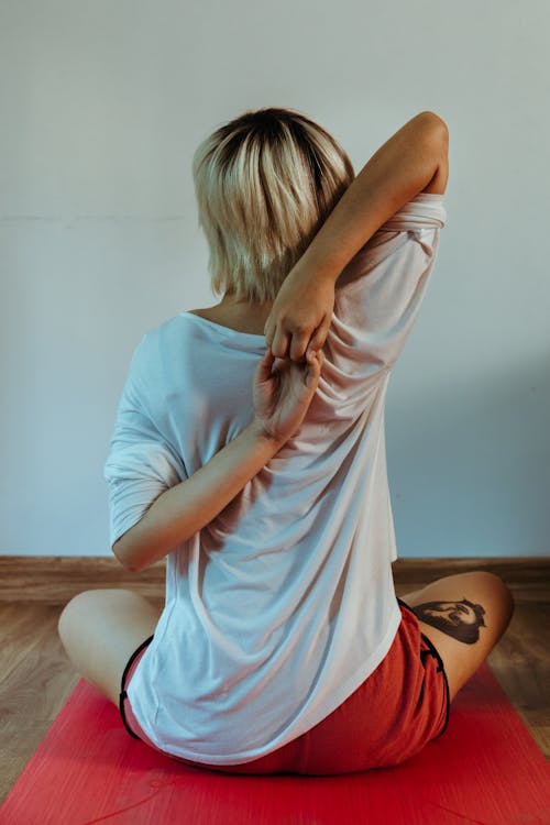 Free Anonymous woman stretching on mat in room Stock Photo