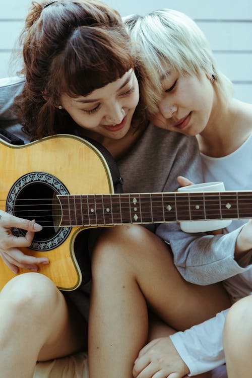 Lesbian couple resting with guitar on terrace