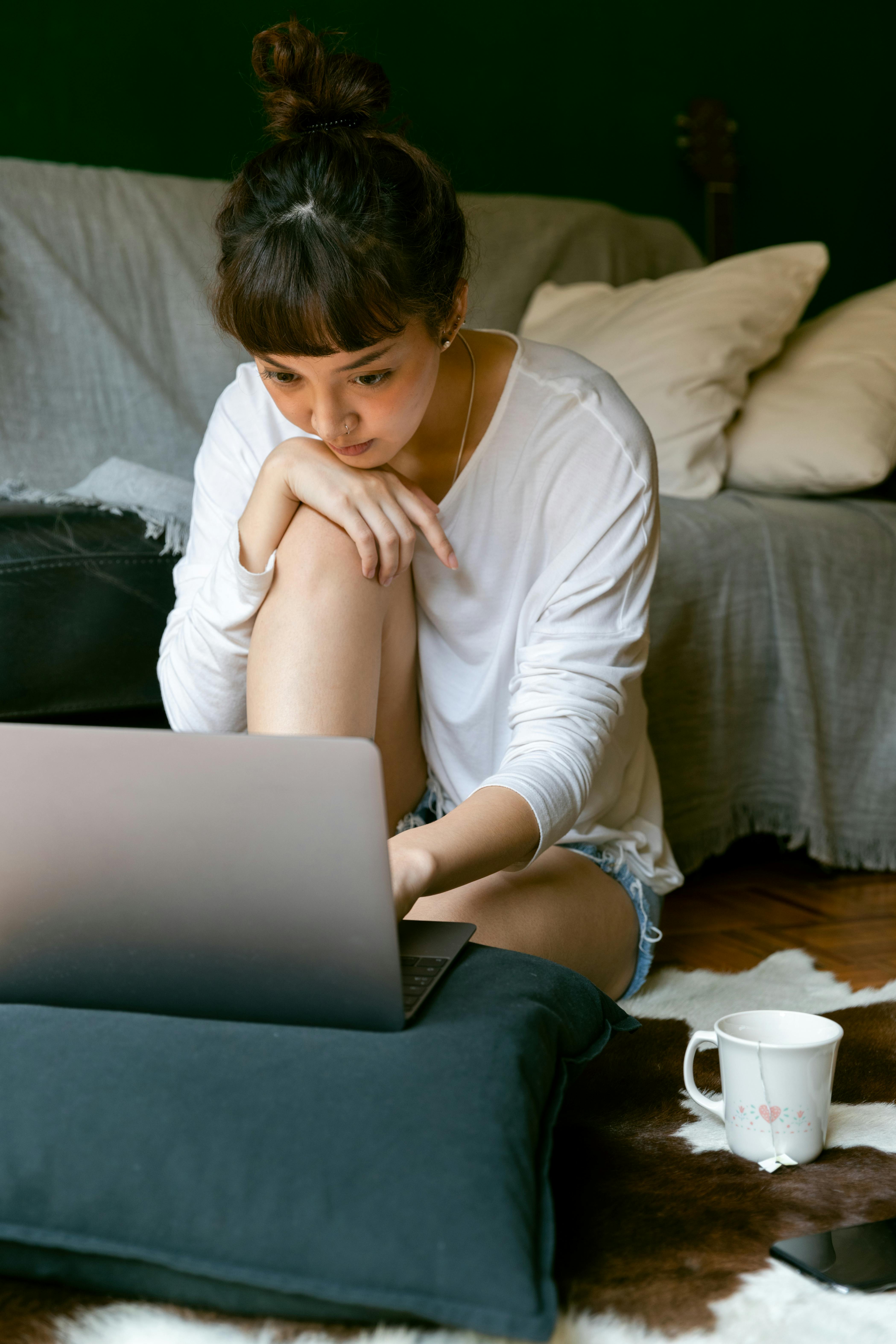 focused ethnic woman using laptop at home