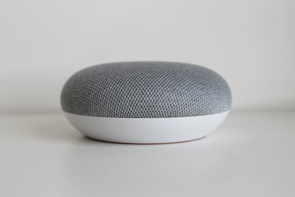 Ultimate Alexa vs Google Smart Speaker Comparison (2025) A close-up shot of a round, minimalist smart speaker on a white surface, highlighting modern design.