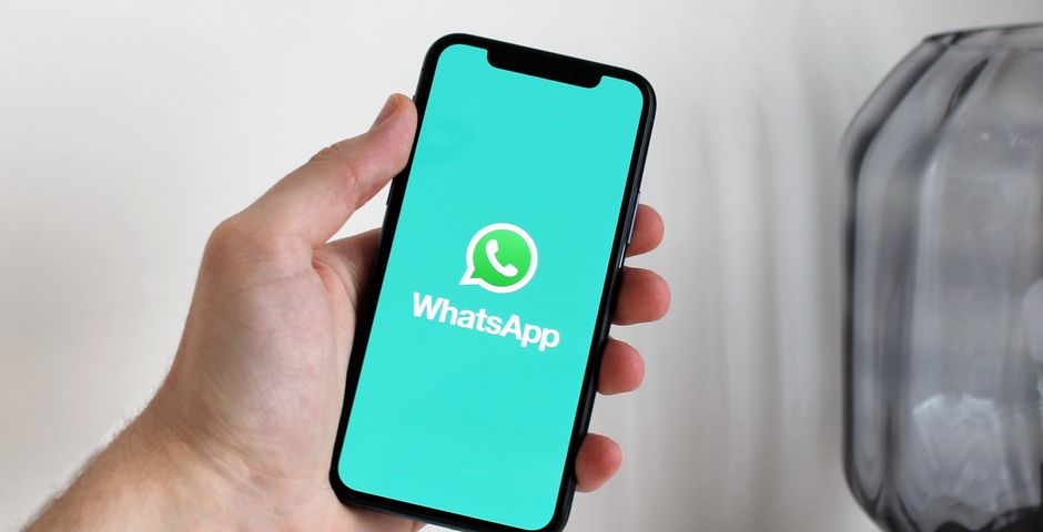 A hand holding a phone open to WhatsApp — how Nomobug books, quotes and replies same-day