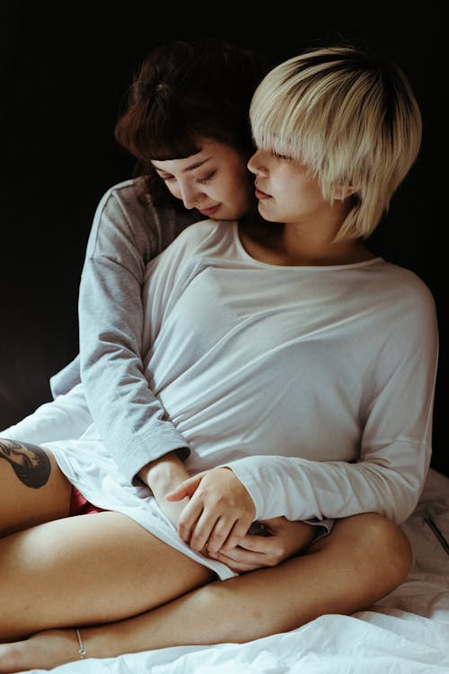 Cuddling Women Sitting on a Bed
