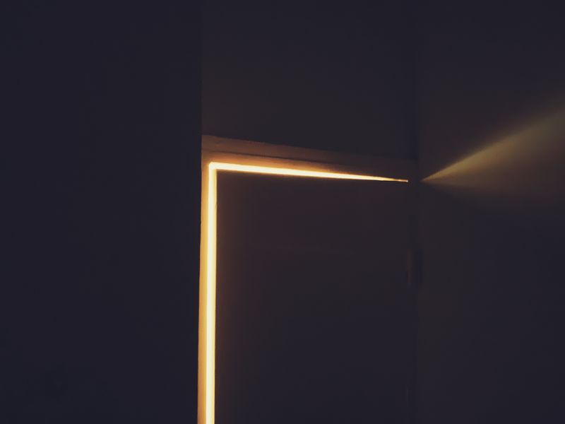 Warm light leaking around a door in a dark room