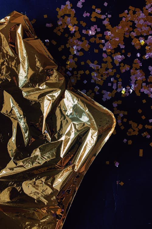 Crumpled golden balloon and confetti