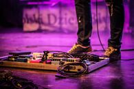 Faceless musician with pedalboard in club