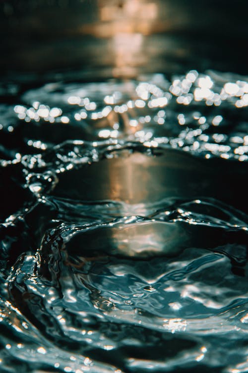 Closeup of crystal clear water splashing in motion with soft sunlight on background