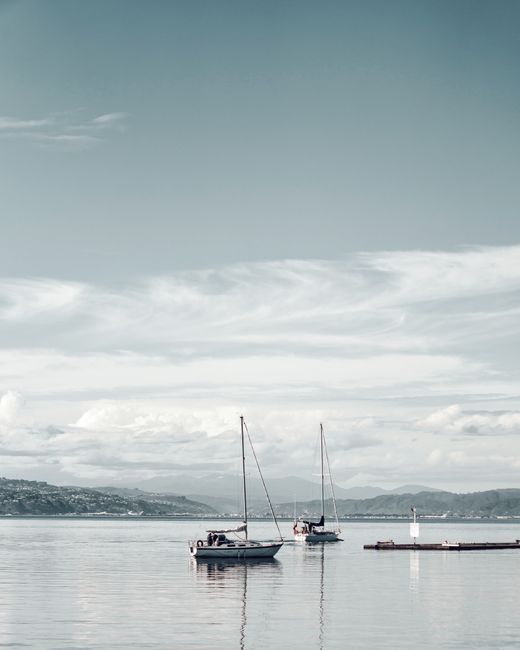 Tranquil scene of sailboats on calm sea with distant coastline, a serene and relaxing atmosphere.