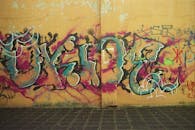 Colorful graffiti on old cement wall above street pavement