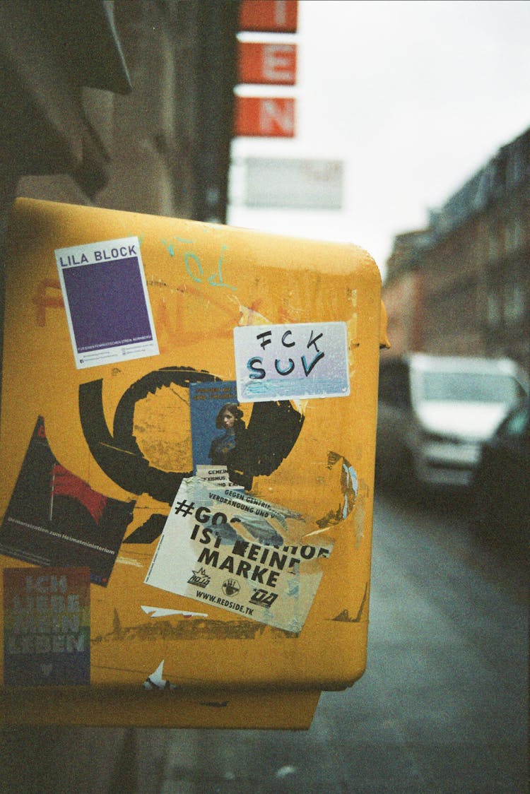 Old Post Box With Stickers On City Street With Cars