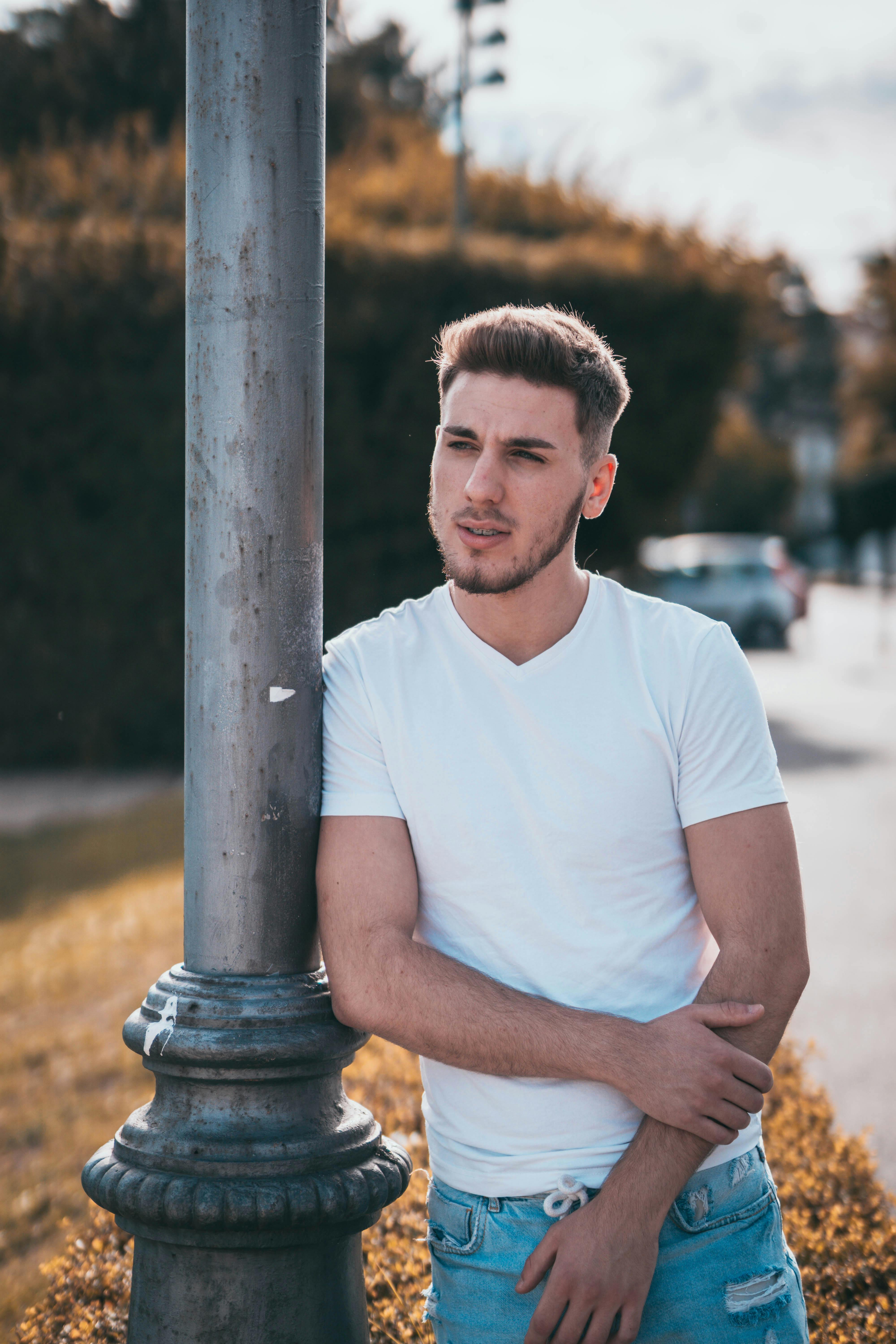 Stylish contemplative man leaning on post near road in fall · Free ...