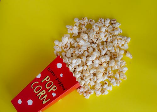 Pack with spilled popcorn on yellow background