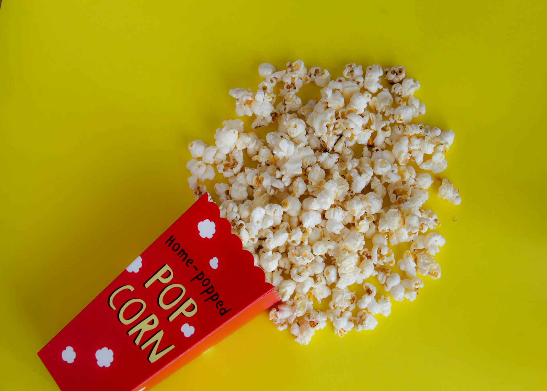 Pack with spilled popcorn on yellow background