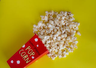 Pack with spilled popcorn on yellow background