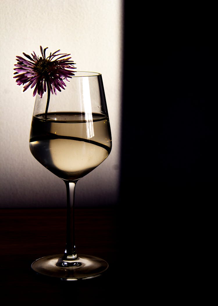 Glass Of White Wine Decorated With Flower In Restaurant