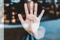 Through glass view of faceless man touching window with hand
