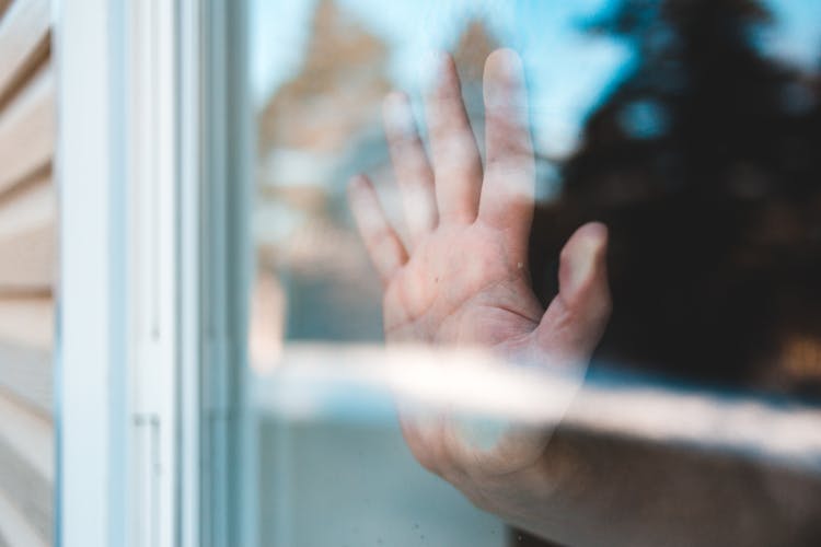 Through Window View Of Faceless Guy Touching Glass With Hand