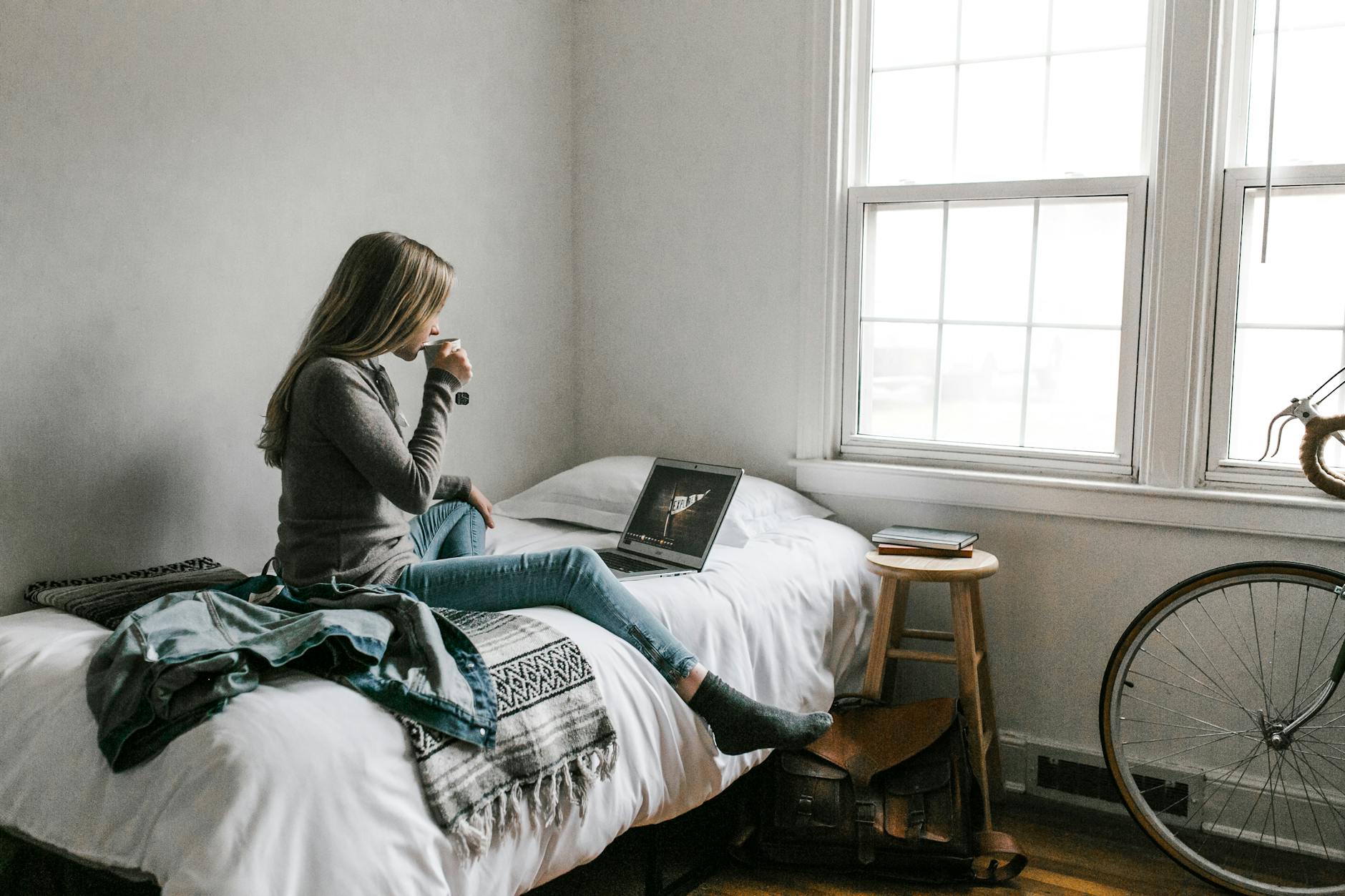Woman in Gray Long Sleeve Shirt Sitting on Bed