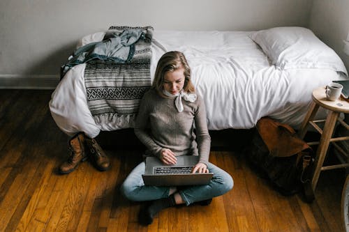 Free Woman in Gray Sweater Sitting on White Couch Stock Photo