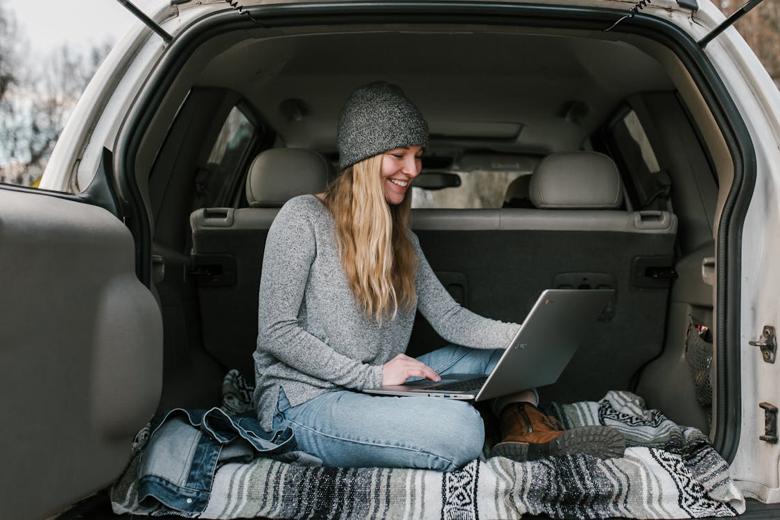 Free Woman in Gray Sweater and Blue Denim Jeans Sitting on Car Seat Stock Photo