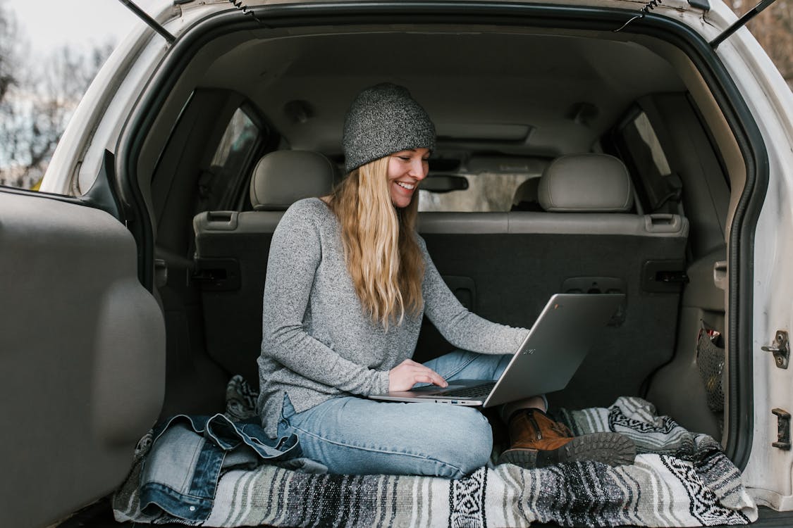 Woman in Gray Sweater and Blue Denim Jeans Sitting on Car Seat