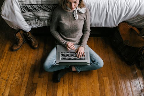 Woman in Gray Sweater Sitting on Couch Using Macbook