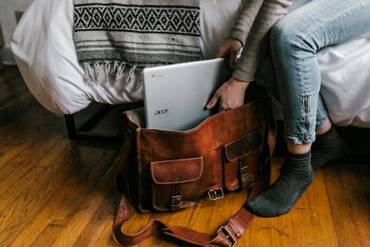 A young woman packs a laptop into a leather bag, embodying remote work lifestyle.