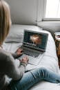 Man and Woman Sitting on Bed Using Macbook Pro