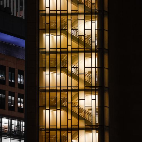 Free Vertical shot of illuminated staircase inside a glass building exterior at night. Stock Photo