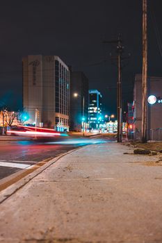 Ground level of shabby pavement near asphalt roadway with modern multistory buildings far away on street illuminated by shining lights in evening