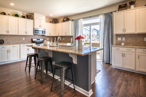 Free A modern, spacious kitchen with a central island, light cabinets, and ample natural light. Stock Photo