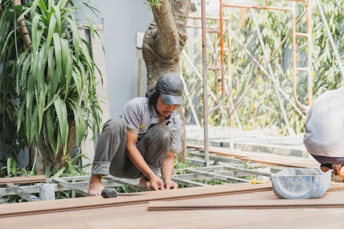 Free Man in Gray Shirt and Cap Working with Wooden Planks Stock Photo