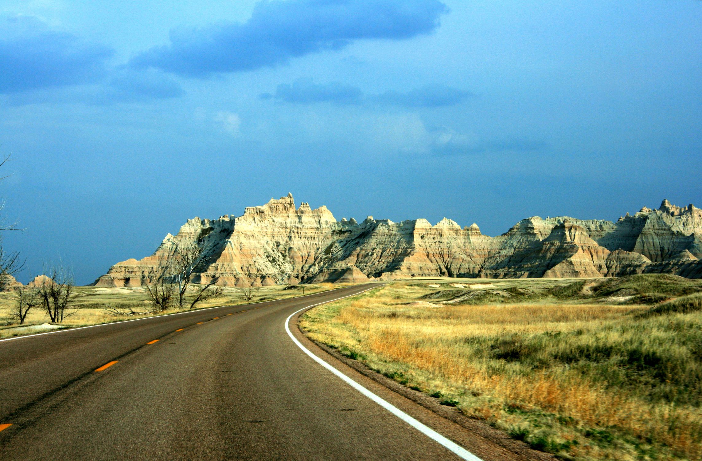 Stunning landscape of Badlands National Park with a winding road under a clear blue sky.