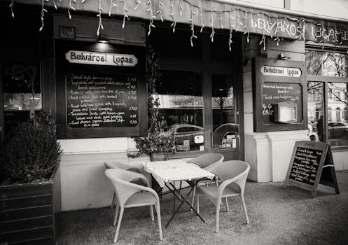 Black and white of street terrace of modern cafeteria with comfortable chairs and menu boards in city