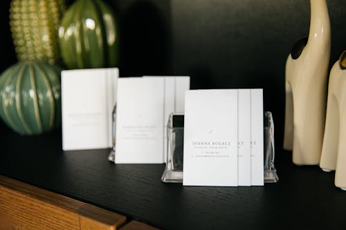 Set of simple visit cards on shelf composed with various stylish vases and decorative figurines in modern office