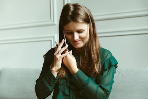 Stylish young female employee talking on smartphone in workspace
