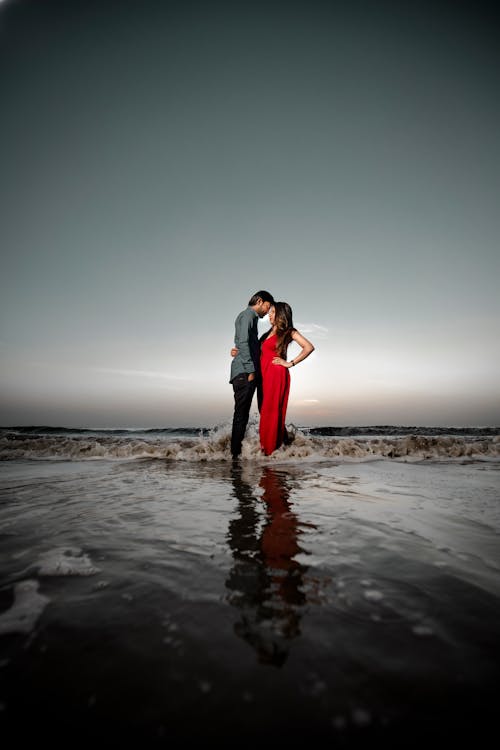 Free A Couple Standing on Beach Stock Photo