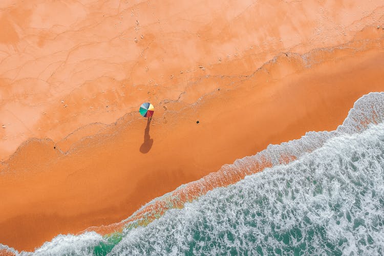 Top View Photo Of Person Holding Colorful Umbrella On Beach