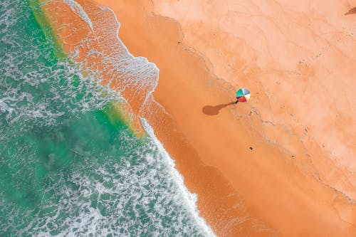 Aerial View of Person Holding Colorful Umbrella on Beach