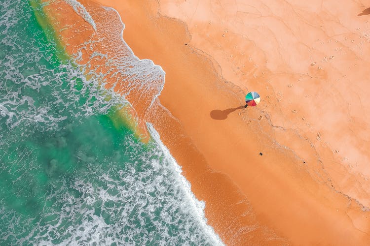 Aerial View Of Person Holding Colorful Umbrella On Beach