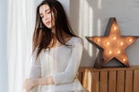 一位年轻女子坐在装饰着星灯的房间里，宁静地陷入沉思