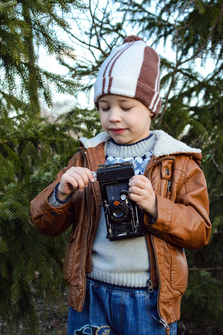 Happy Little Kid Using Retro Photo Camera In Woods