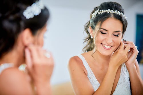 Bride Smiling while Putting on Earrings
