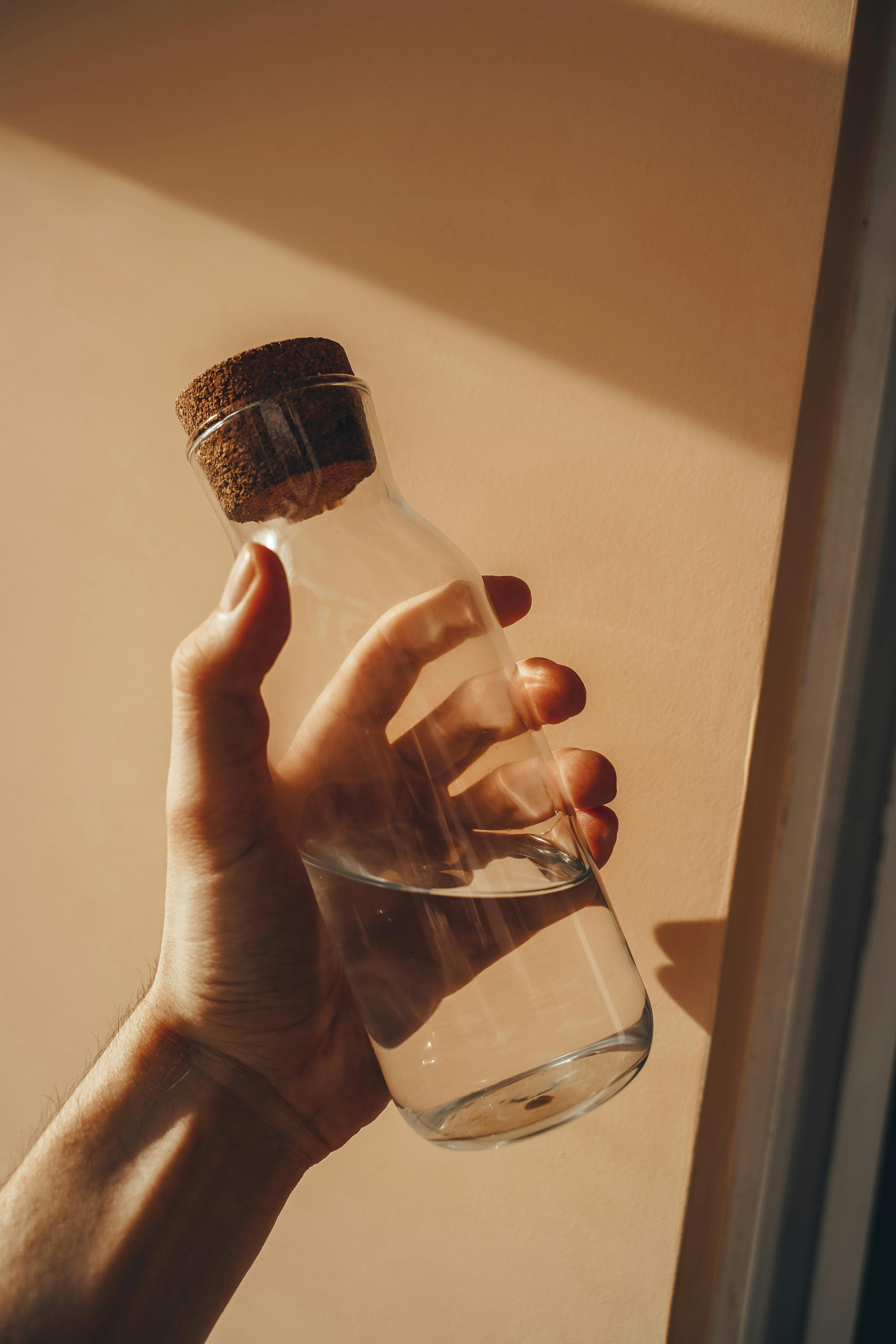 Photo of a Person's Hand Holding a Glass Bottle with Water · Free Stock  Photo